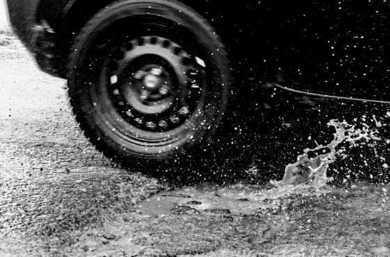 gros plan d'une roue de véhicule qui passe sur un nid de poule